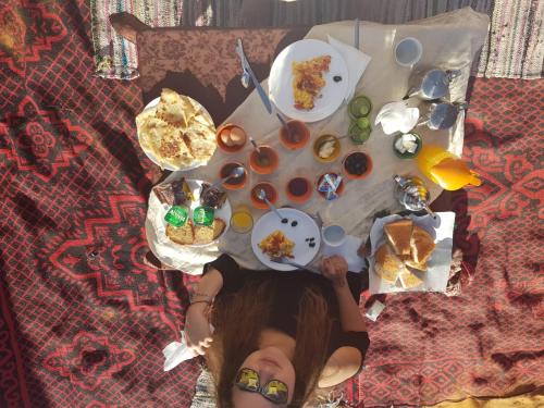 a woman sitting at a table with plates of food at Berber Camp in Merzouga