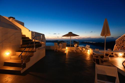 a balcony with stairs and chairs and an umbrella at Ilioperato Hotel in Imerovigli