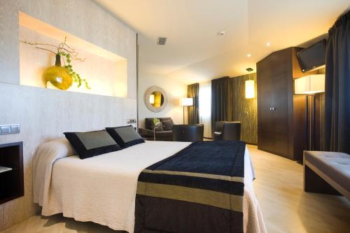 ルーゴにあるHotel Torre de Núñezのベッドとリビングルームが備わるホテルルームです。