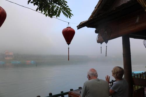 a man and a woman sitting in front of a body of water at Phong Nha Coco House in Phong Nha