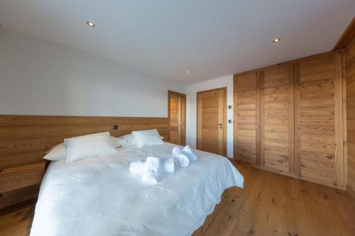 a bedroom with a large white bed with wooden cabinets at Oak Tree Chalet - on the ski slope - luxury! in Nendaz