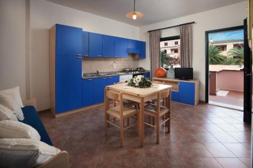 卡拉利貝羅托的住宿－Appartamenti Le Ginestre e Gli Oleandri，厨房配有蓝色橱柜和桌椅