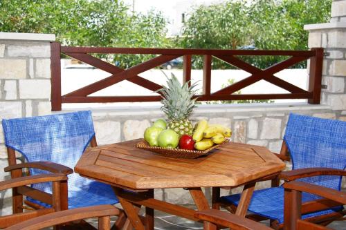 a basket of fruit on a wooden table with chairs at Anna Platanou Hotel in Parikia