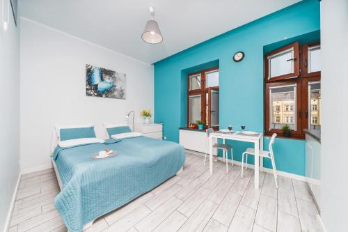 niebieska sypialnia z łóżkiem i stołem w obiekcie K12 Apartments w Krakowie