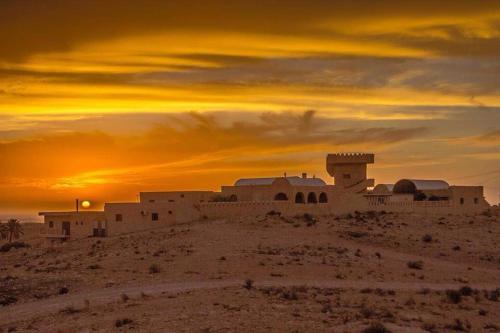 a building in the desert with a sunset in the background at Dar Ayed Tamezret in Tamezret
