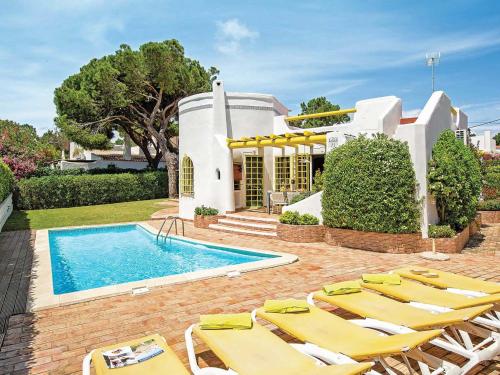 ヴィラモウラにあるTranquil Villa in Vilamoura with Private Swimming Poolのスイミングプール、黄色のラウンジチェアが備わるヴィラです。