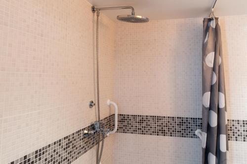 a bathroom with a shower with black and white tiles at The Originals City, Hôtel Éden, Rouen Nord in Bois-Guillaume