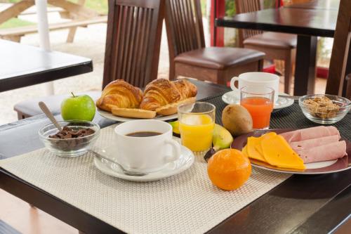 a table with a breakfast of croissants apples oranges and orange juice at The Originals City, Hôtel Éden, Rouen Nord in Bois-Guillaume