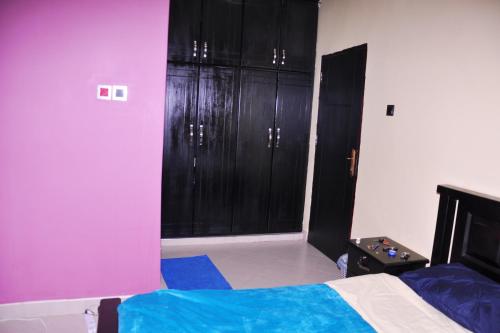 a bedroom with purple and black cabinets and a bed at Seguku Katale Apartment 1 in Katale