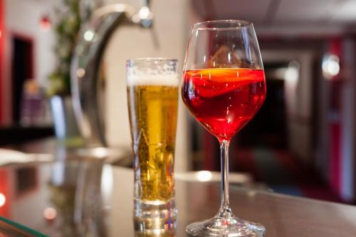 a glass of wine and a glass of beer on a counter at The Originals City, Hôtel Éden, Rouen Nord in Bois-Guillaume
