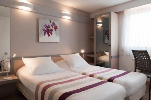 a hotel room with two beds and a window at The Originals City, Hôtel Éden, Rouen Nord in Bois-Guillaume