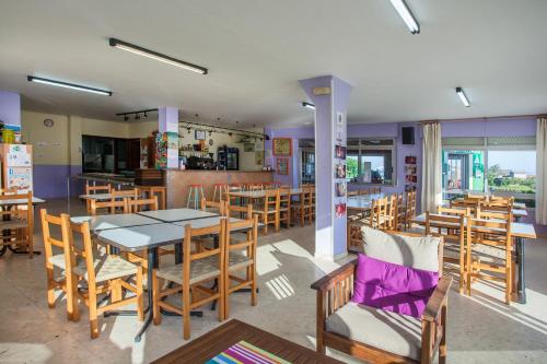 un restaurante con mesas y sillas de madera y una cocina en Camping Os Fieitás en O Grove