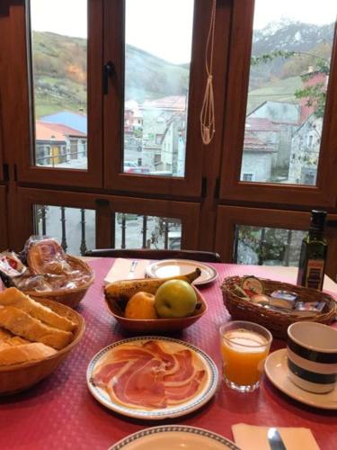 Una mesa con comida y pan sobre una mesa con ventanas. en Hotel Rural Peña Castil, en Sotres