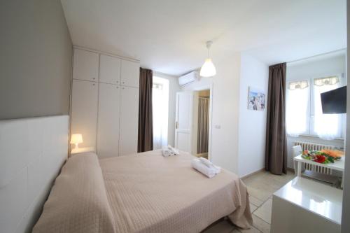 ein weißes Schlafzimmer mit einem Bett und einem Fernseher in der Unterkunft DIMORA AMALFITANA in Monopoli