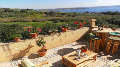 a patio with tables and chairs and a view of the ocean at Great Seaviews Location - FREE Gozo taxi service, Fast WIFI, Bicycles, BBQ & Parking, No Car needed in Għajnsielem