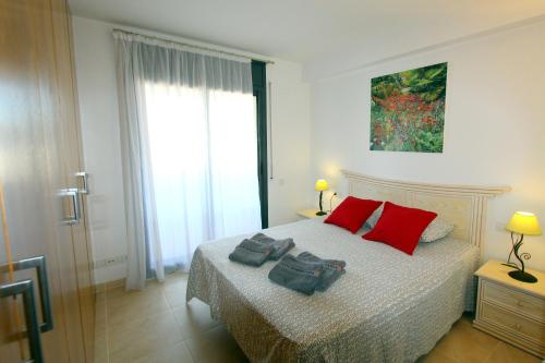 エンプリアブラバにあるLEON INMO Apartment Oasis - 10022のベッドルーム1室(赤い枕のベッド1台付)