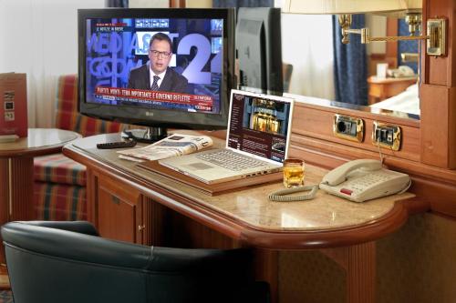 a desk with a laptop computer and a television at Hotel Capitol Milano in Milan
