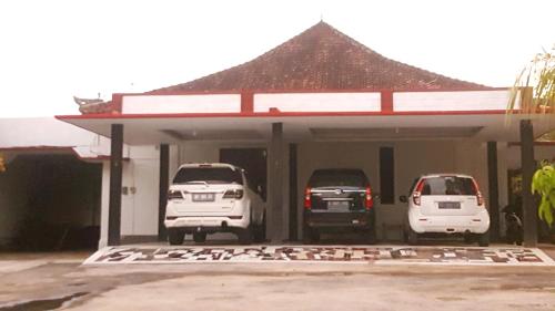 two cars parked in front of a car garage at HOTEL SEGARA MANDALA in Negara