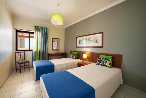 um quarto de hotel com duas camas e uma cadeira em RR Club Amarilis em Portimão