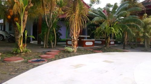 a house with palm trees in front of it at HOTEL SEGARA MANDALA in Negara