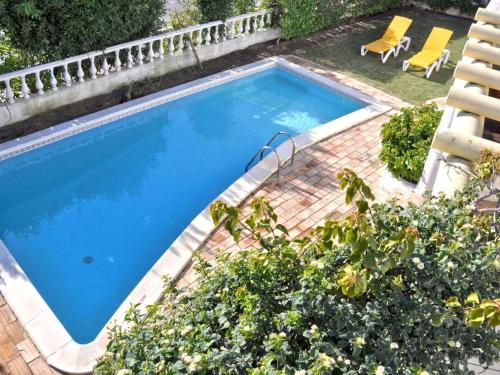 ヴィラモウラにあるTranquil Villa in Vilamoura with Private Swimming Poolの椅子と植物のあるスイミングプールの景色を見渡せます。