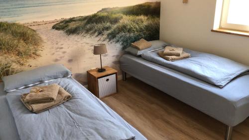 AltenmedingenにあるFerienhaus “ Lille Hyggehytte“のビーチの絵画が飾られた部屋のベッド2台