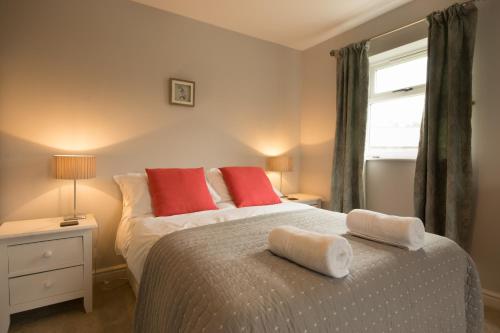 マトロックにあるHardwick Cottage- Darwin Lake Holiday Villageのベッドルーム1室(赤い枕のベッド1台、窓付)