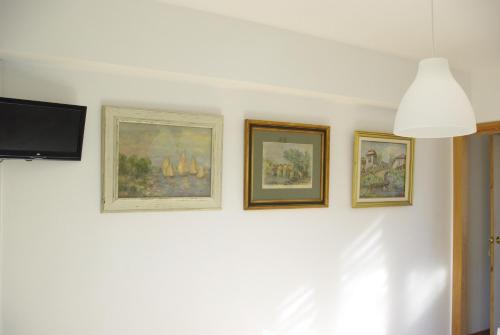 four paintings on a white wall with a tv at Prau Riu Hotel Hyundai-Asturdai in Llanes