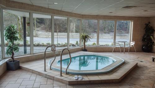 a large swimming pool in a room with windows at Bowfield Hotel and Spa in Howwood