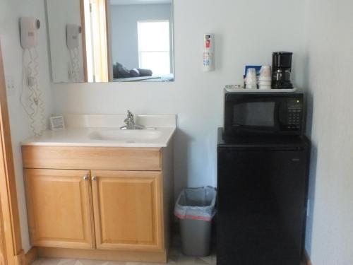 a small kitchen with a sink and a microwave at Scarborough Inn in Manteo