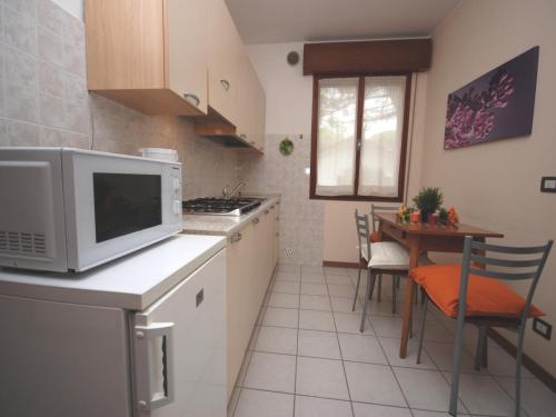 una cucina con forno a microonde e tavolo con sedie di Villa Tiziano a Lignano Sabbiadoro