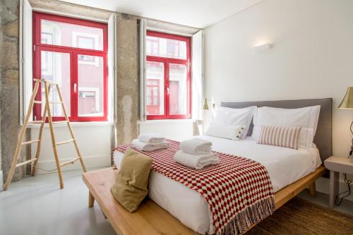 a bedroom with a bed with a ladder and two windows at Oporto Sweet Home I in Porto