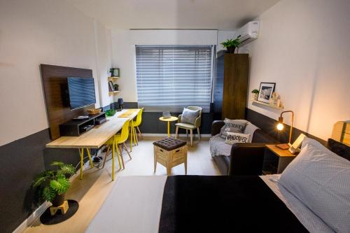 a living room with a bed and a desk in a room at Meu lugar na Cidade Baixa in Porto Alegre