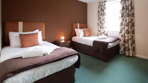 a hotel room with two beds and a window at The Spires Serviced Apartments Aberdeen in Aberdeen