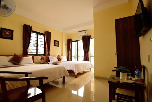 two beds in a room with yellow walls and windows at Guest House Maika in Hue