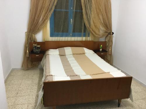 a bed in a bedroom with a window and curtains at Sidi Mansour Route Touristique in Sfax