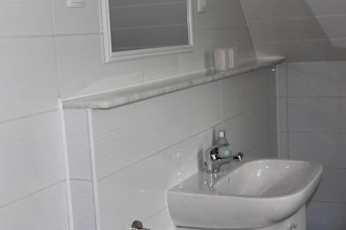 een witte badkamer met een wastafel en een spiegel bij Ferienwohnung in der Natur in Drolshagen
