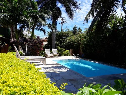 una piscina en un patio con 2 sillas y árboles en Vila Shalimar, en Búzios