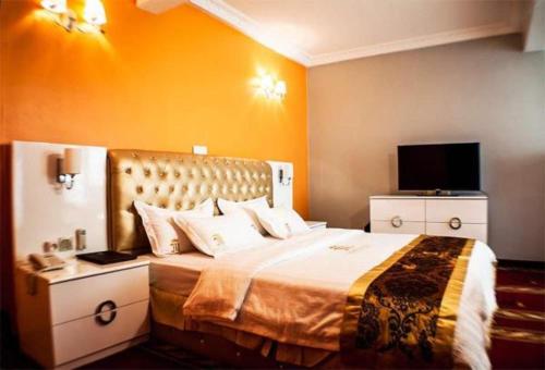a hotel room with a bed and a flat screen tv at Mbayaville Hotel in Douala