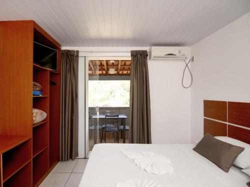 a bedroom with a bed and a window with a table at Pousada Vale da Montanha in Serra Negra