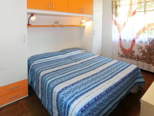 a bedroom with a bed with a blue and white blanket at Tra i Pini in Lignano Sabbiadoro