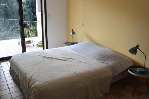 a bed in a bedroom with two tables and a window at FILETTA in Sari Solenzara
