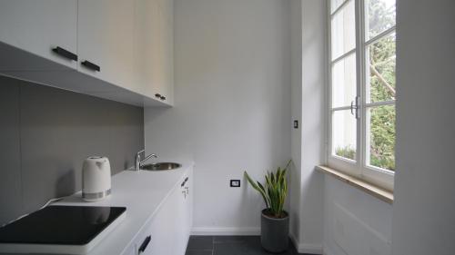 a white kitchen with a sink and a window at Destil B&B in Tirana