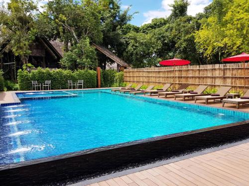 a large swimming pool with chairs and umbrellas at PAN KLED VILLA eco hill resort in Chiang Rai