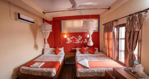two beds in a room with red walls at Jungle Wildlife Camp in Sauraha