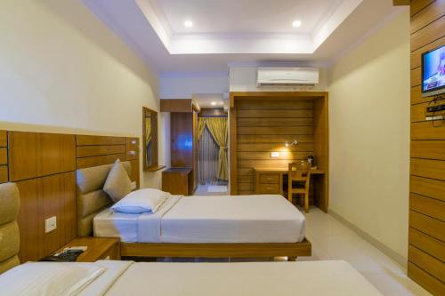 a hotel room with two beds and a television at Sree Gokulam Residency in Trichūr