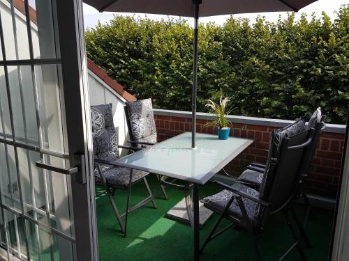 a table and chairs on a balcony with an umbrella at Giese FeWo Küstenglück in Hasselberg