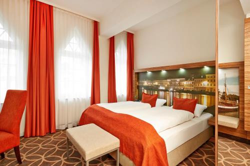 a hotel room with a bed and a chair at H+ Hotel Lübeck in Lübeck