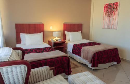 a hotel room with two beds and a chair at Convair Hotel in Ciudad del Este