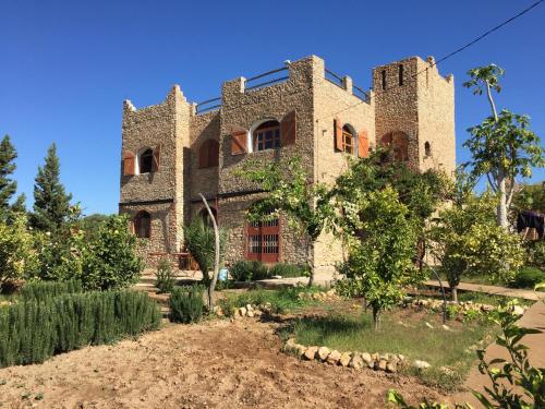 an old stone building with a garden in front of it at Aziki in Essaouira